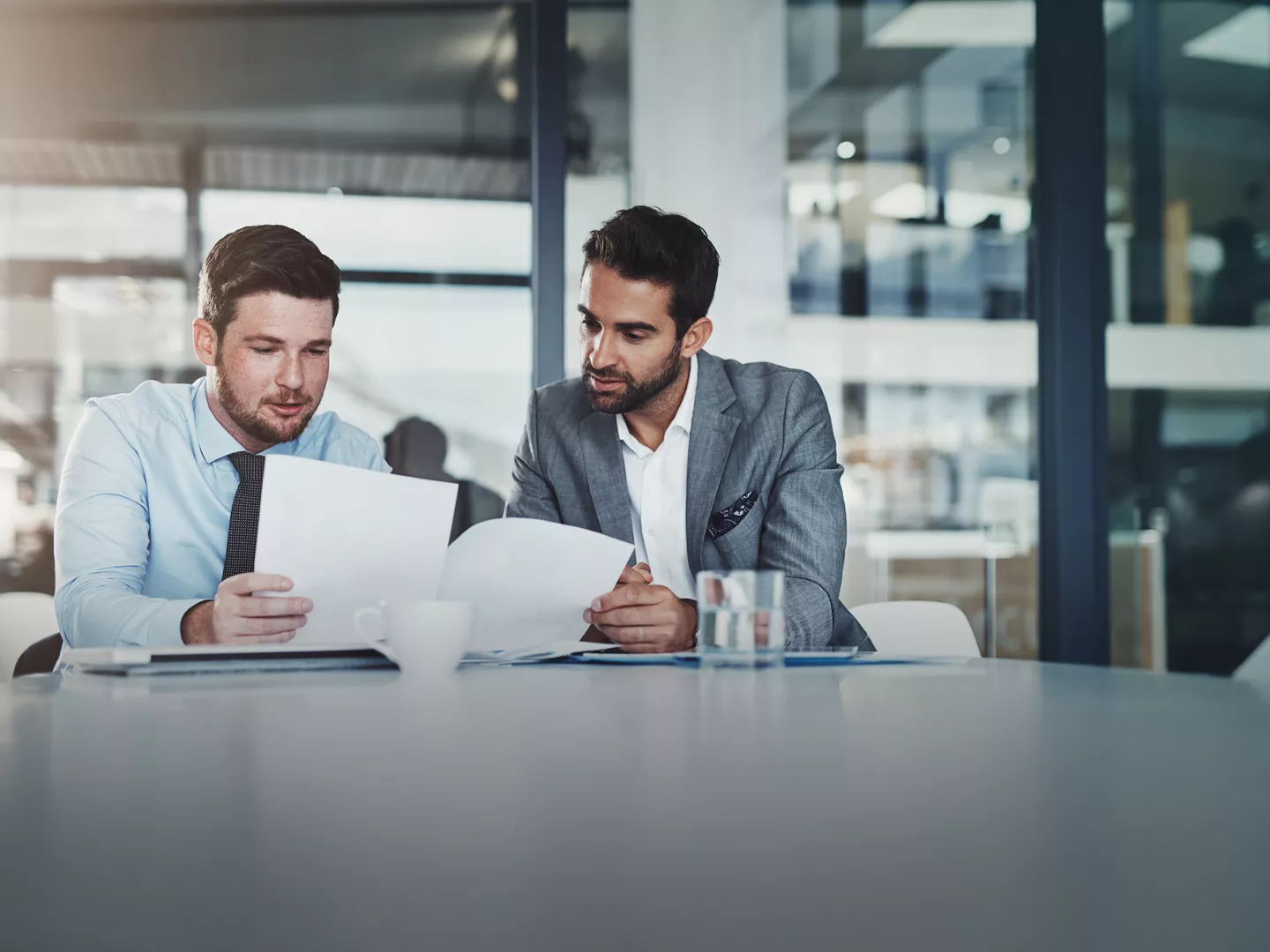 Meeting, documents and businessmen in discussion in the office boardroom planning a corporate strategy. Brainstorming, collaboration and male employees working on project with paperwork in workplace.